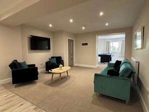 A living room with a flat-screen TV, two sofas, a coffee table, and a pool table. - East Halton Hotel (East Halton)