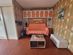 A room with a sofa, a small table with a bowl, a white bench, a TV, and a patterned wall. - Studio with terrace near the beach in Collioure (Collioure)