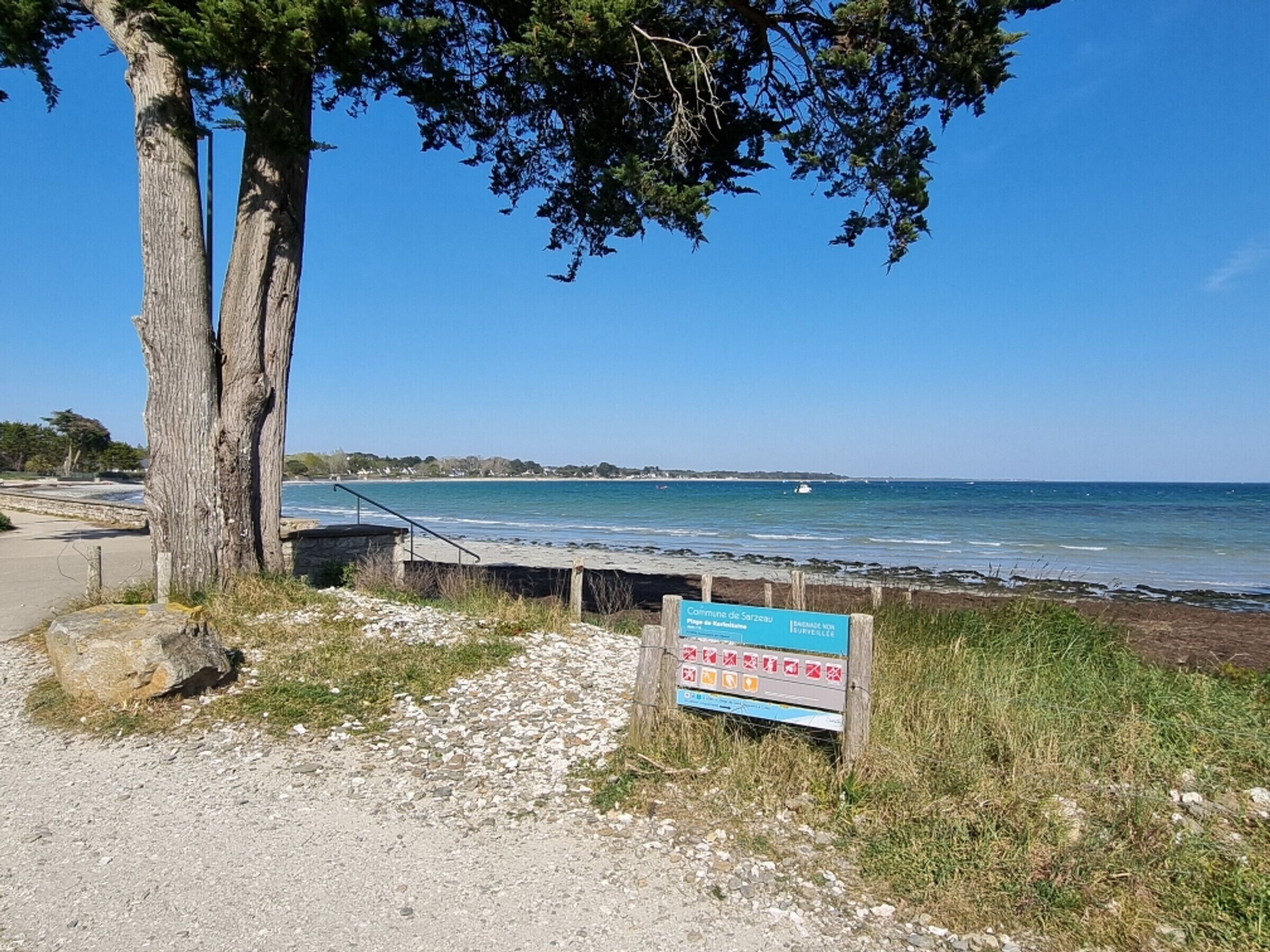 A coastal path with a sign indicating 'Comunidade de Sarzedo' and a view of the sea.