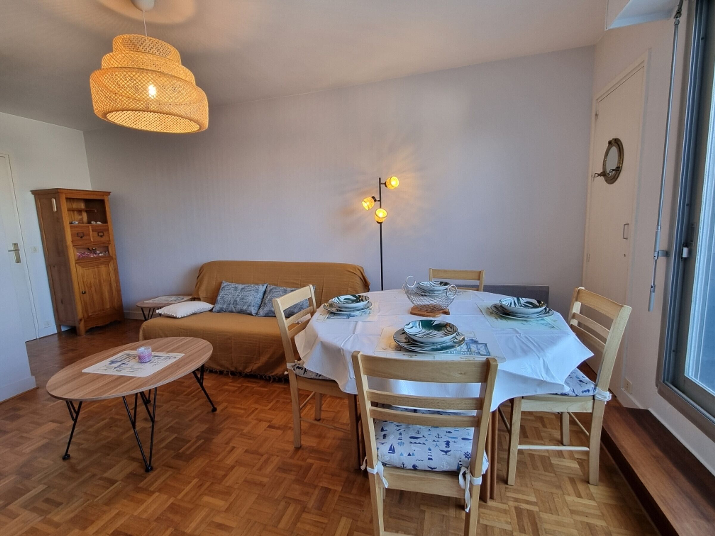 Ruokailutila, jossa on pyöreä pöytä, tuoleja, sohva ja puinen kaappi.