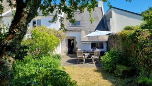 A house with a stone entrance, a patio with a table and chairs, and a garden area with various plants. - Charming fisherman's house, 4 pers, near beach, Saint-Gildas-de-Rhuys, wifi (Saint-Gildas-de-Rhuys)
