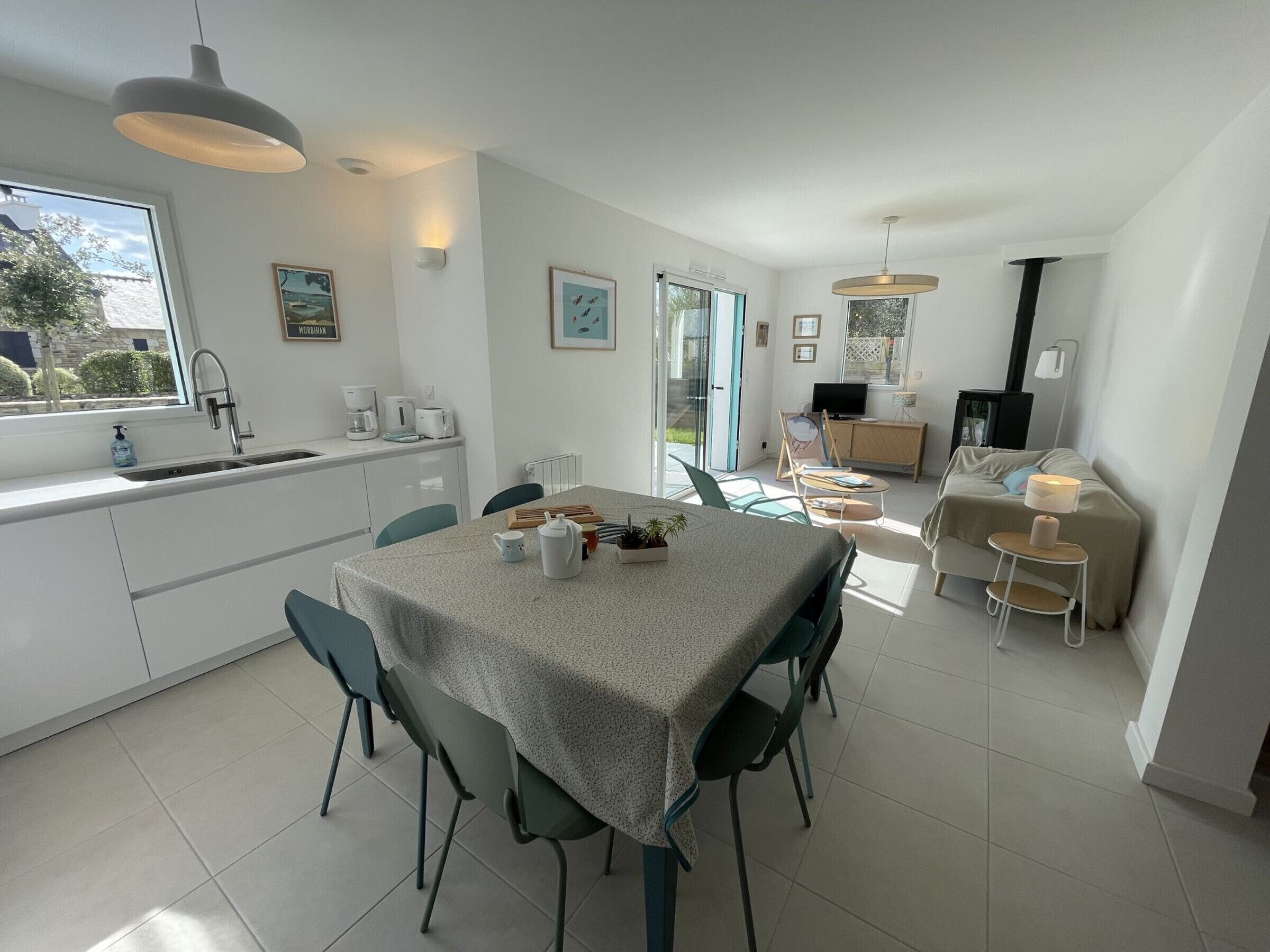 A modern kitchen with a dining area, a sofa, and a TV.