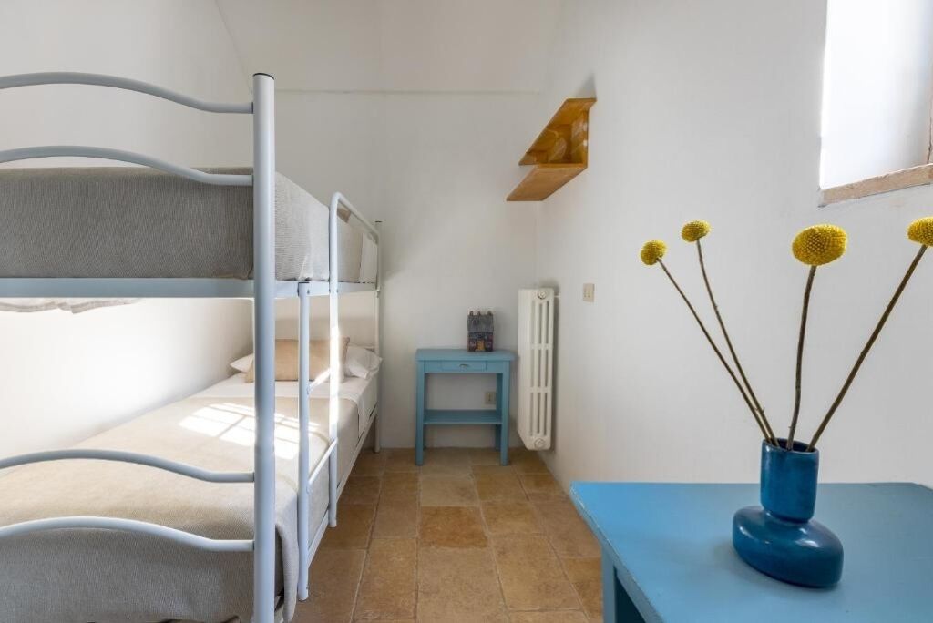 Un dormitorio con literas, una pequeña mesa con un florero y un radiador.
