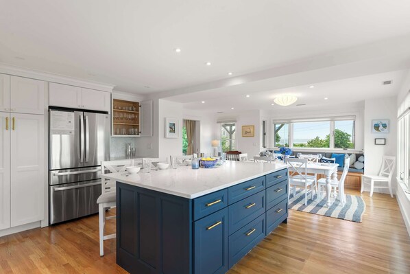 A modern kitchen with white cabinetry, a stainless steel refrigerator, and a blue island with drawers.