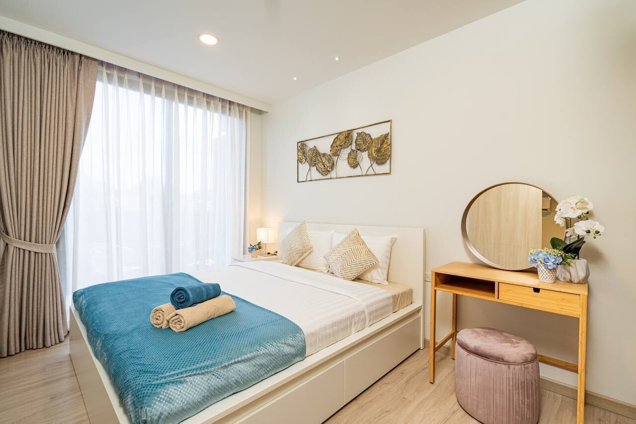 A modern hotel room with a bed, bedside table, and a round mirror.