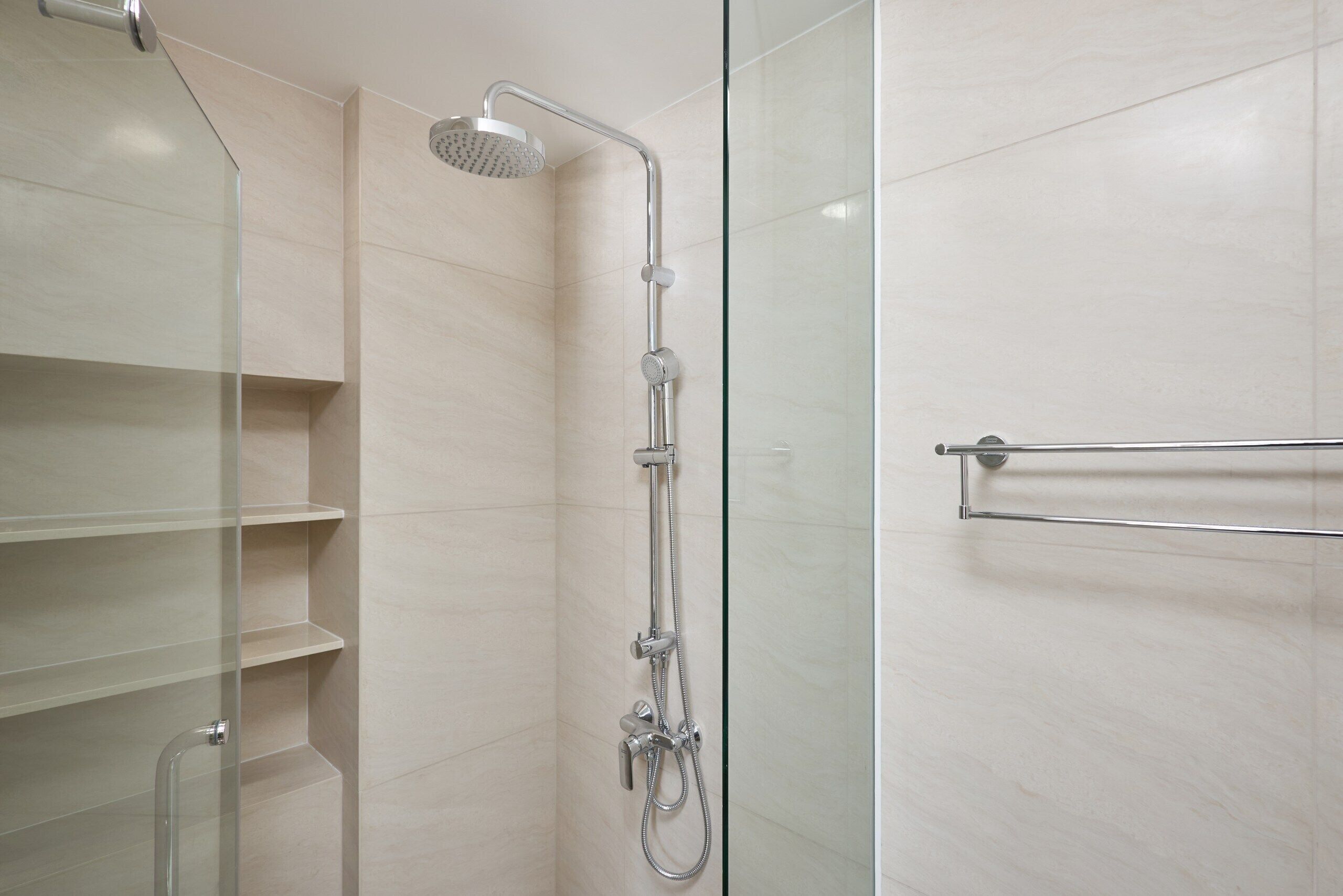 A modern shower with a glass enclosure, a handheld showerhead, and a towel rack.