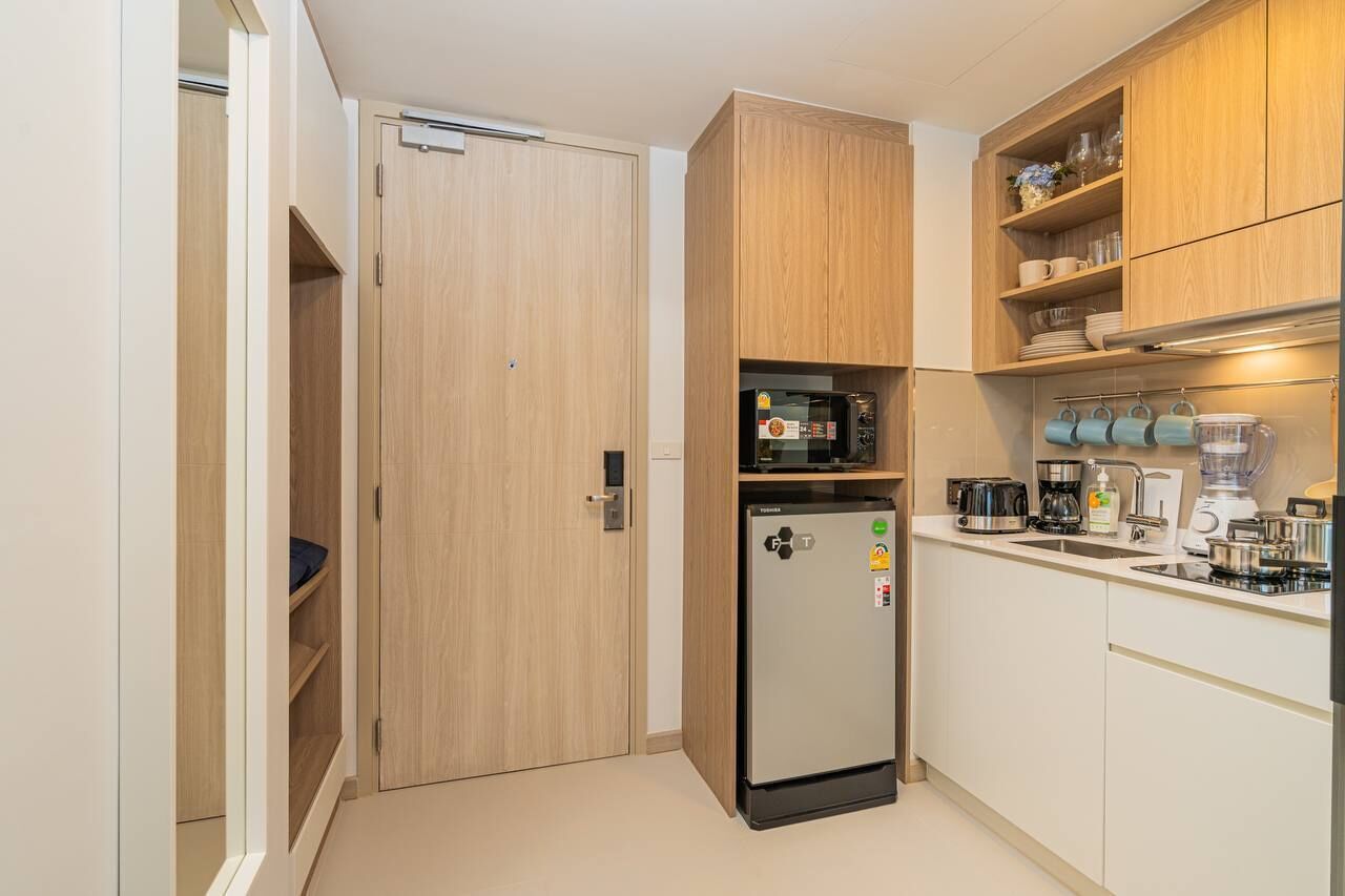 A compact kitchen with a built-in refrigerator, microwave, and coffee maker.