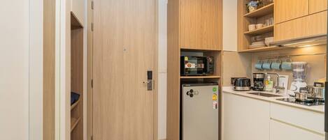 A compact kitchen with a built-in refrigerator, microwave, and coffee maker.