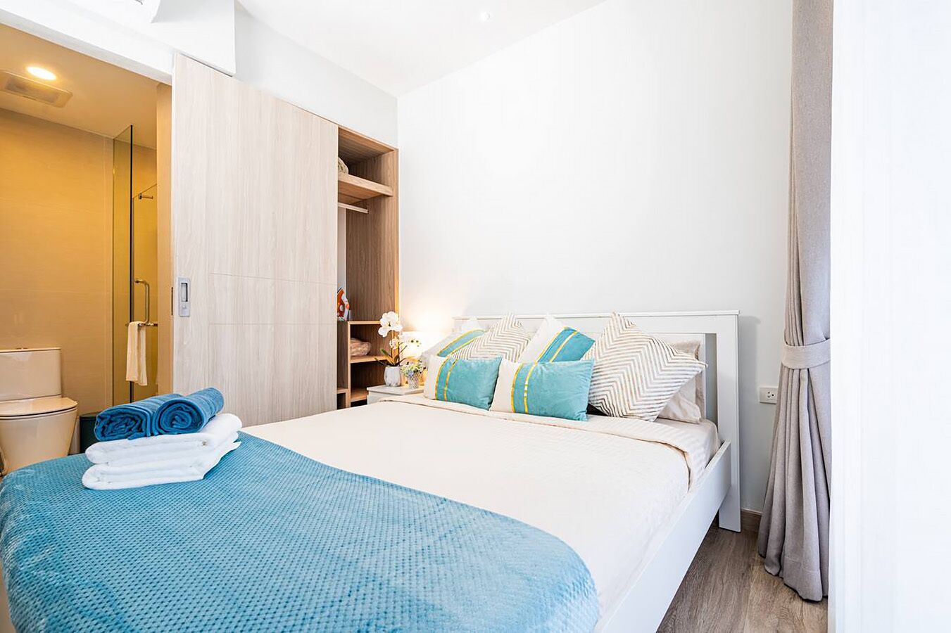 A hotel room with a bed, a bathroom, and a wardrobe.