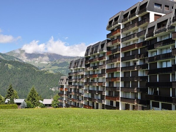 A multi-story hotel with balconies, set against a mountainous backdrop. - Cozy ski-in studio with parking, pets allowed (Notre-Dame-de-Bellecombe)