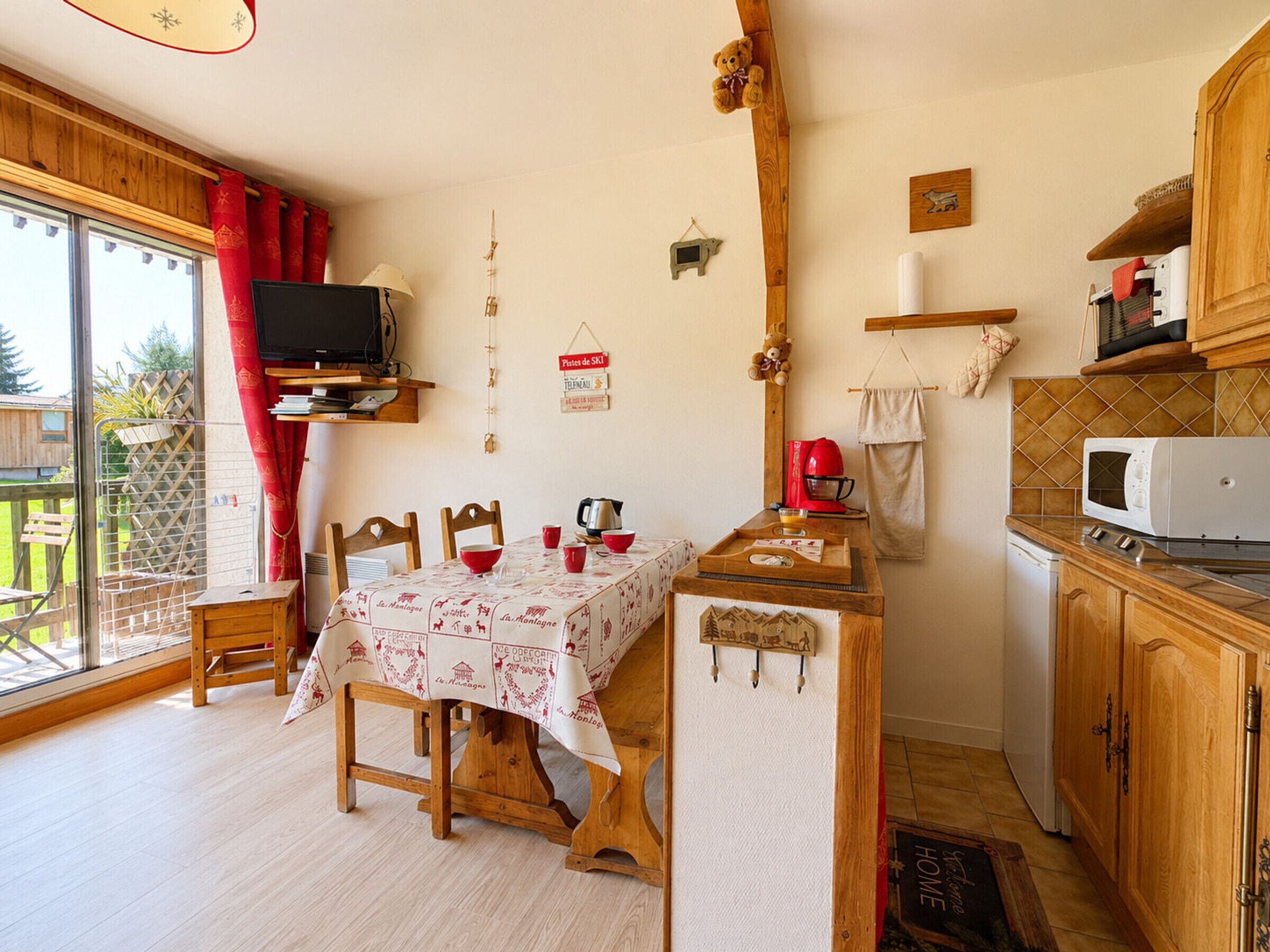 A cozy kitchen with a dining table, chairs, a TV, and a microwave.