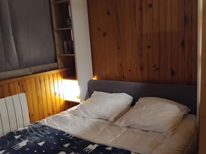 A bedroom with a wooden headboard, a bed with white bedding, and a nightstand.