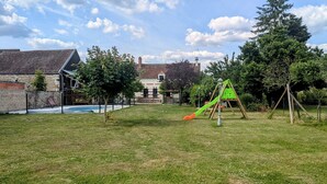 A backyard with a swimming pool, a wooden play structure, and a house with a sloped roof. - Rural charm and relaxation near Loire castles (Chabris)