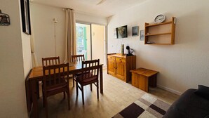 Ein Essbereich mit Tisch, Stühlen, einem Deckenventilator, einem Fernseher und einer kleinen Holzeinrichtung.