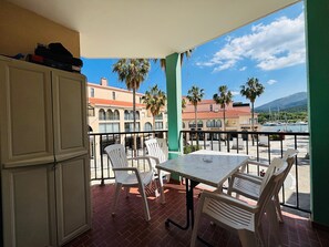 A balcony with a table and chairs, overlooking a marina with boats and palm trees. - Apartment at Argelès-sur-Mer port with terrace and parking (Argelès-sur-Mer)