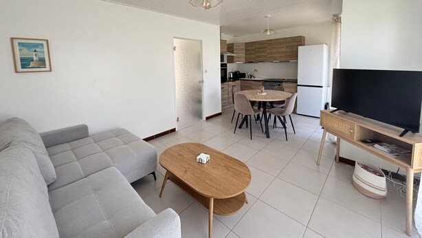 A modern living room with a grey sofa, a wooden coffee table, and a TV on a wooden stand. - House in Les Sables-d'Olonne with garden, 4 sleeps (Les Sables-d'Olonne)