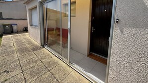 A residential building with a sliding glass door entrance, a garage door, and a small outdoor area with a tiled floor. - House in Les Sables-d'Olonne with garden, 4 sleeps (Les Sables-d'Olonne)