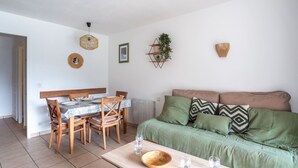 Un comedor con una mesa y sillas de madera, un sofá verde y un pequeño cuenco de madera sobre una mesa.