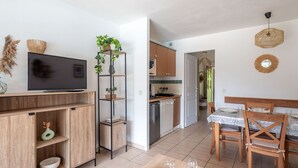 Una cocina moderna con armarios de madera, horno empotrado y comedor con mesa y sillas.