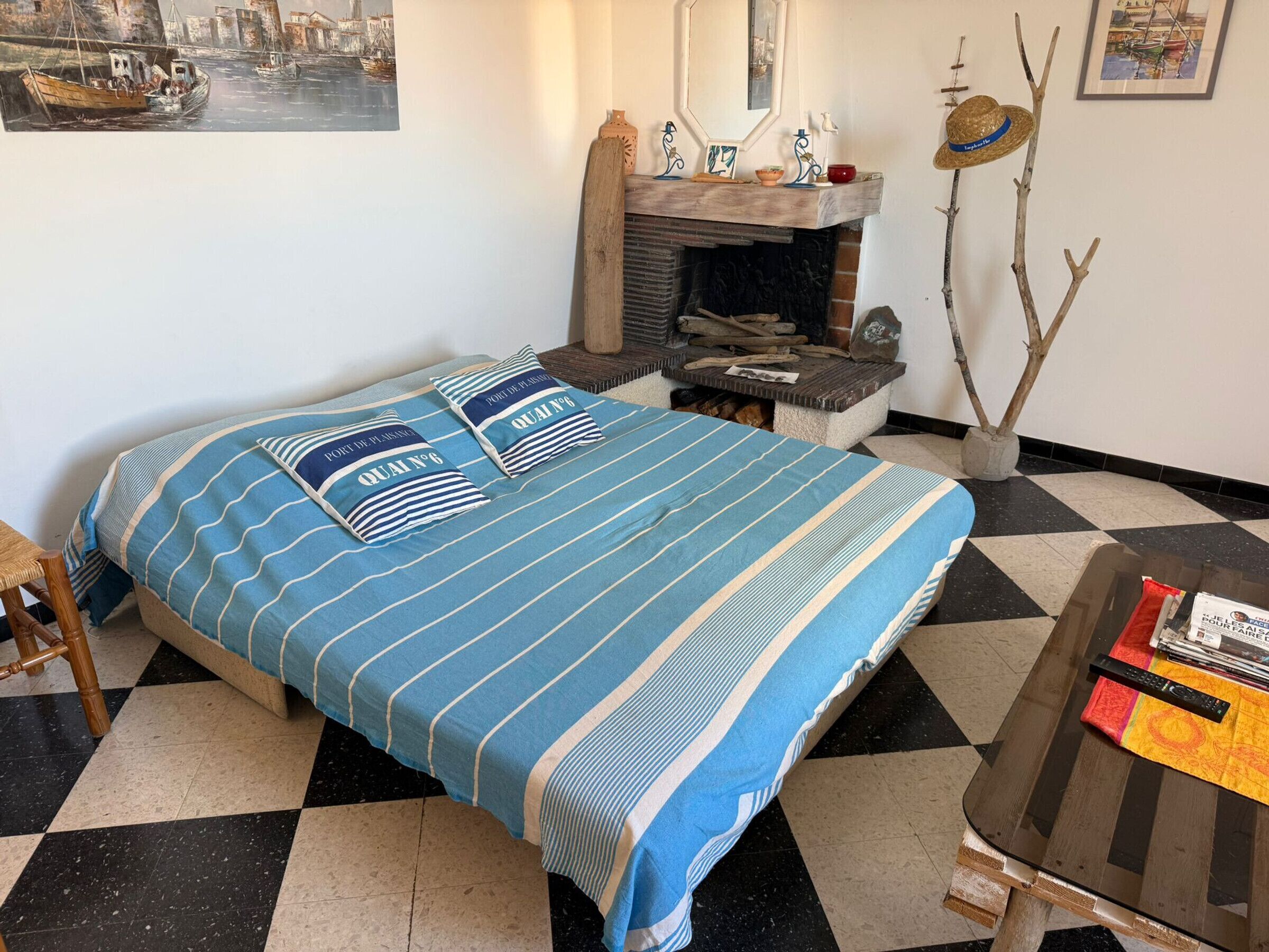A bedroom with a bed, a small table, a fireplace, and a painting on the wall.