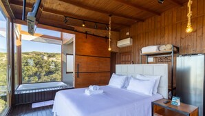Un dormitorio con una cama grande, una mesita de noche, una lámpara colgante y un equipo de aire acondicionado.