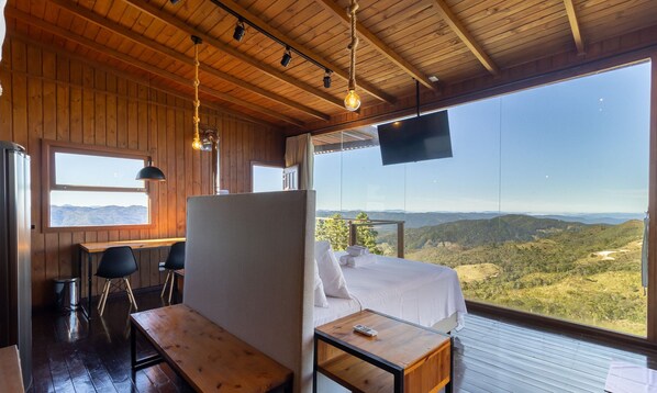 Ein Zimmer mit Bett, Schreibtisch und Blick auf eine Berglandschaft.