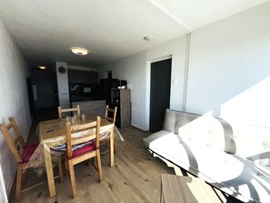 A compact living space with a dining table, chairs, a sofa, and a kitchenette.
