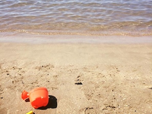 Ein sandiger Strand mit einem einzelnen orangefarbenen Gegenstand im Sand.