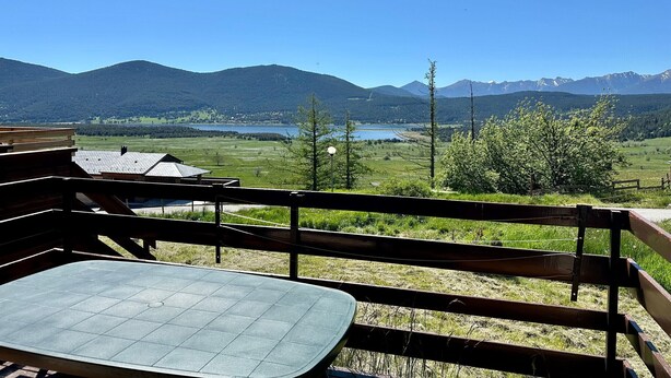 A view from a balcony with a table and chairs, overlooking a lake, mountains, and a village. - Duplex T4 Apartment 60sqm, 6 Pers, Lake & Mountain View (Les Angles)