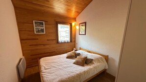 A small, cozy bedroom with a wooden ceiling, a single bed with a white duvet, and two framed pictures on the wall. - Duplex T4 Apartment 60sqm, 6 Pers, Lake & Mountain View (Les Angles)