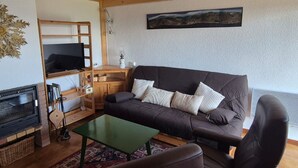 A cozy living room with a dark brown sofa, a green coffee table, and a fireplace. - Duplex T4 Apartment 60sqm, 6 Pers, Lake & Mountain View (Les Angles)