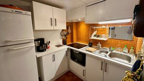 A compact kitchen with white cabinets, a black stove, and a tiled backsplash. - Duplex T4 Apartment 60sqm, 6 Pers, Lake & Mountain View (Les Angles)