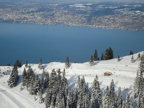 Paisaje nevado con un lago y una cabaña pequeña.