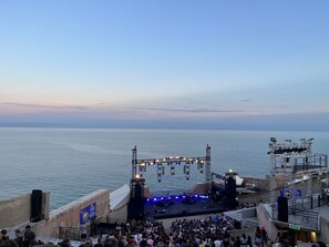 A stage with a crowd, overlooking a body of water.