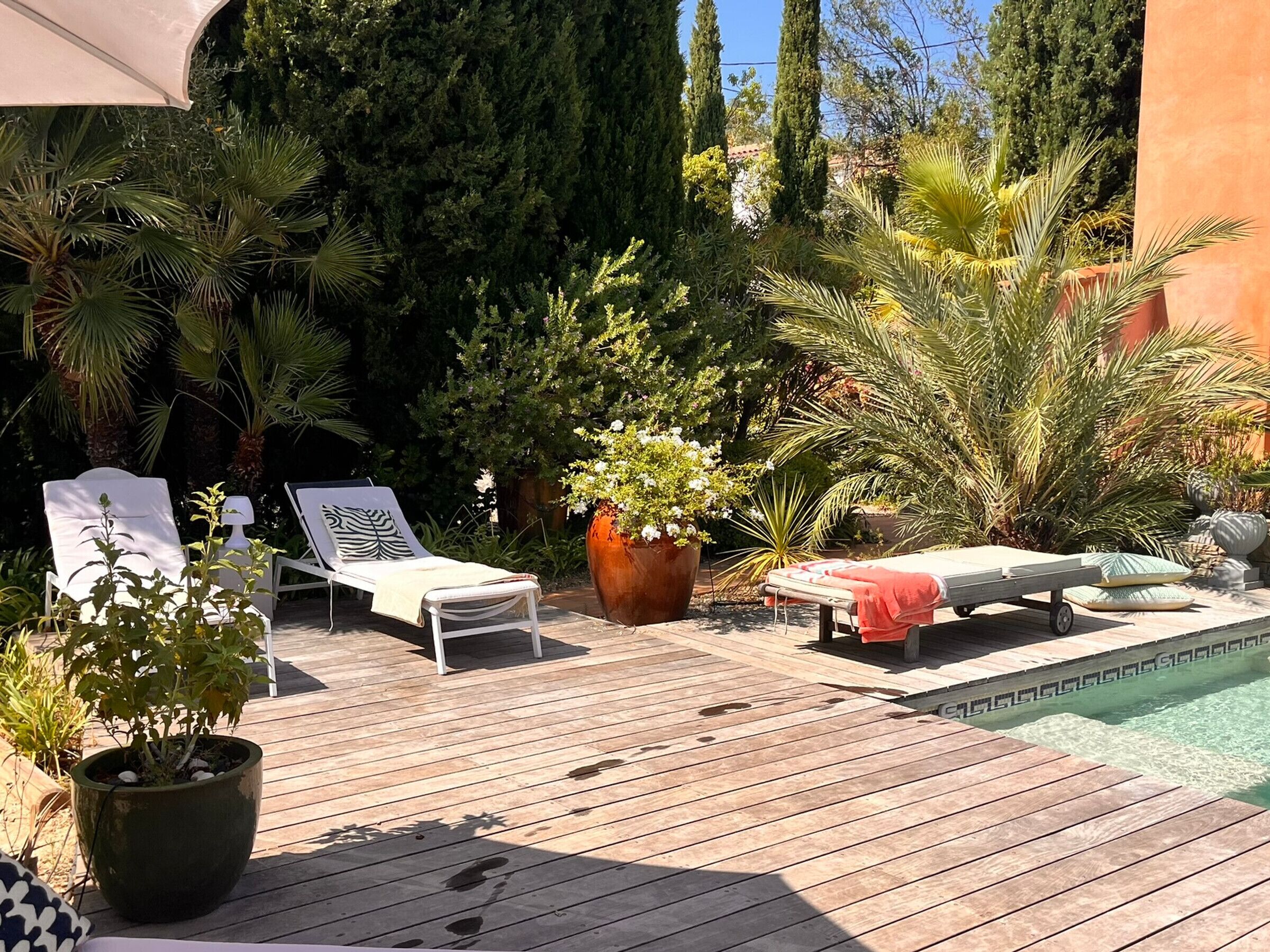 Une terrasse en bois avec des chaises longues et une petite piscine.