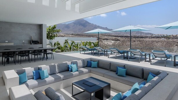A modern outdoor living area with a pool, seating, and a view of a mountainous landscape.