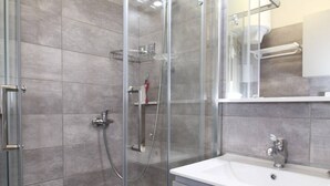 Une salle de bain moderne avec une douche à parois de verre, un lavabo blanc et un miroir au-dessus du lavabo.