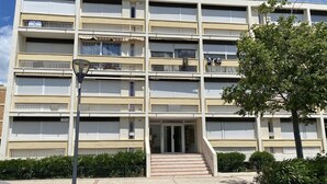Un immeuble résidentiel à plusieurs étages, doté de balcons, d’une entrée principale et d’un espace de stationnement.