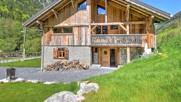 A wooden chalet with a stone foundation, a balcony, and a view of a mountainous landscape. - Chalet for 16 with fireplace and pets allowed, near cable car in Morzine (Morzine)