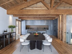 Een moderne keuken met een groot kookeiland, witte stoelen en een eettafel.