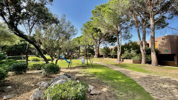Ein Park mit Spielgeräten, Bäumen und einem gepflasterten Weg.