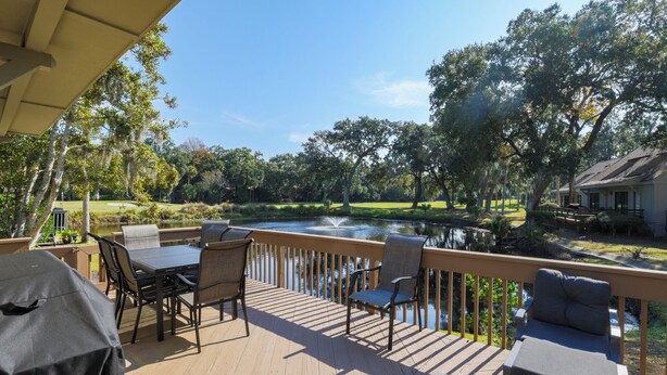 Terraza de madera con mobiliario exterior con vistas a un estanque y un campo de golf.