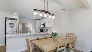 Una cocina moderna con electrodomésticos de acero inoxidable, una isla central con asientos y una lámpara colgante.