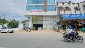 Een modern hotel met een grote glazen gevel en een bord waarop 'HOTEL ORIGIN' staat.