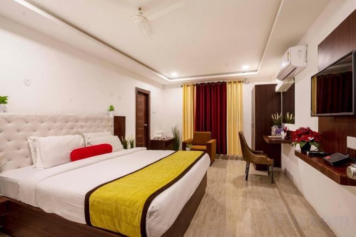 A hotel room with a bed, a desk, a chair, and a television.