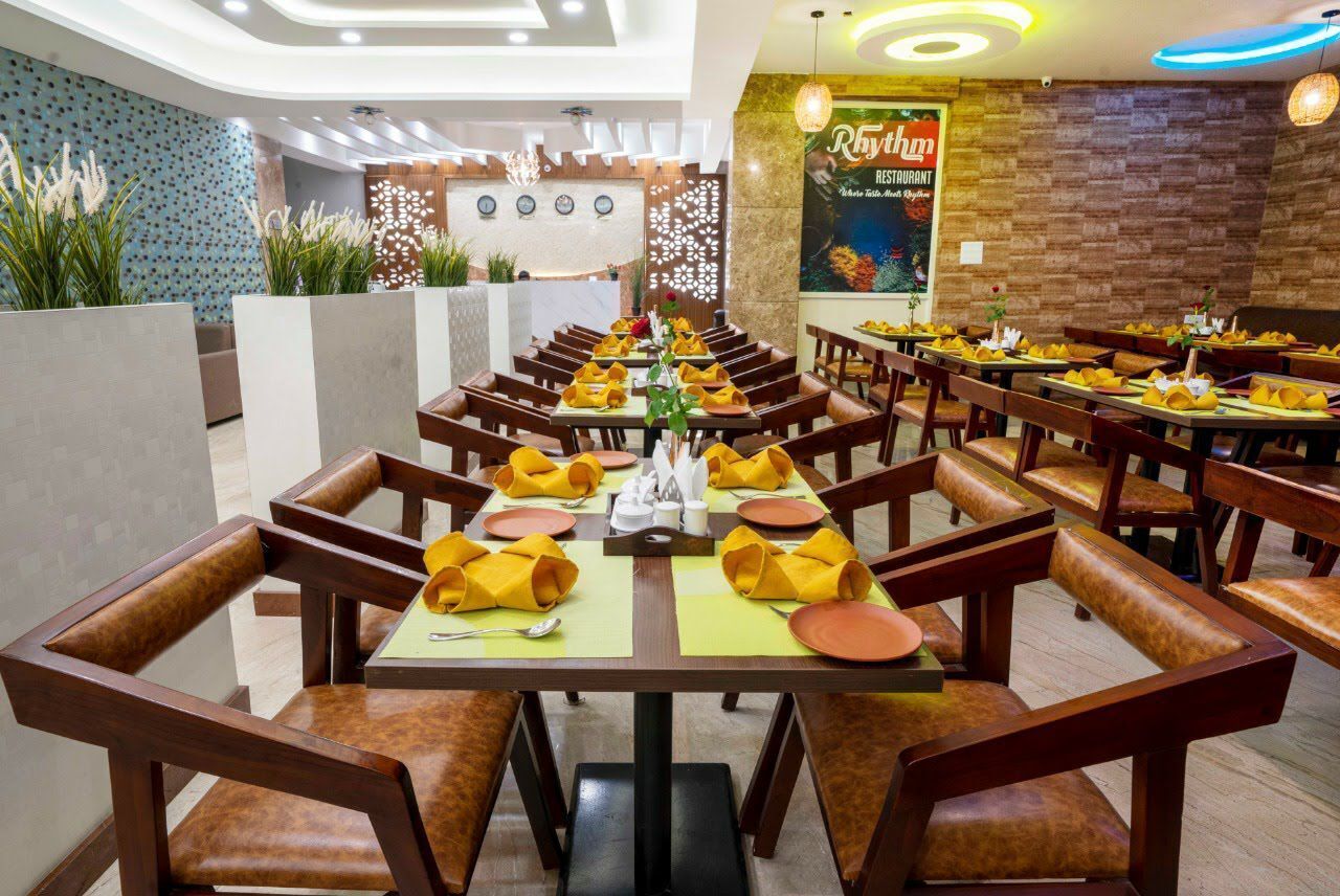 A restaurant with a long dining table set with yellow napkins, brown leather chairs, and a wooden floor.