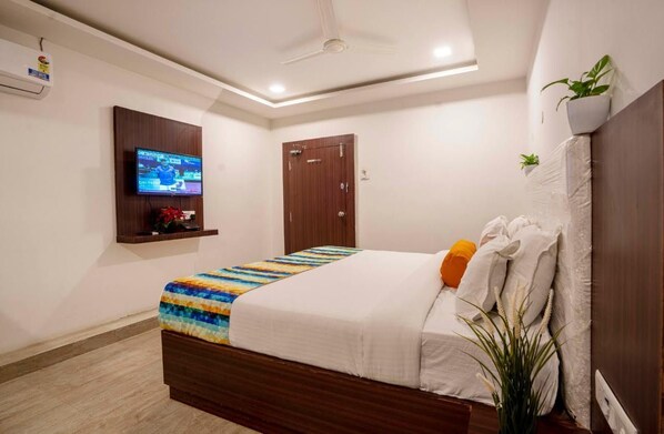 A bedroom with a bed, a TV mounted on the wall, a ceiling fan, and a door. - Hotel ORIGIN Hyderabad Airport (Hyderabad)