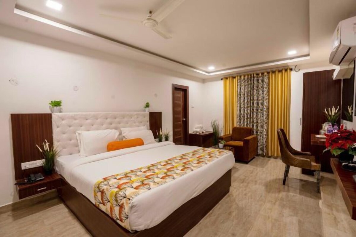 A hotel room with a large bed, a desk, and a chair.