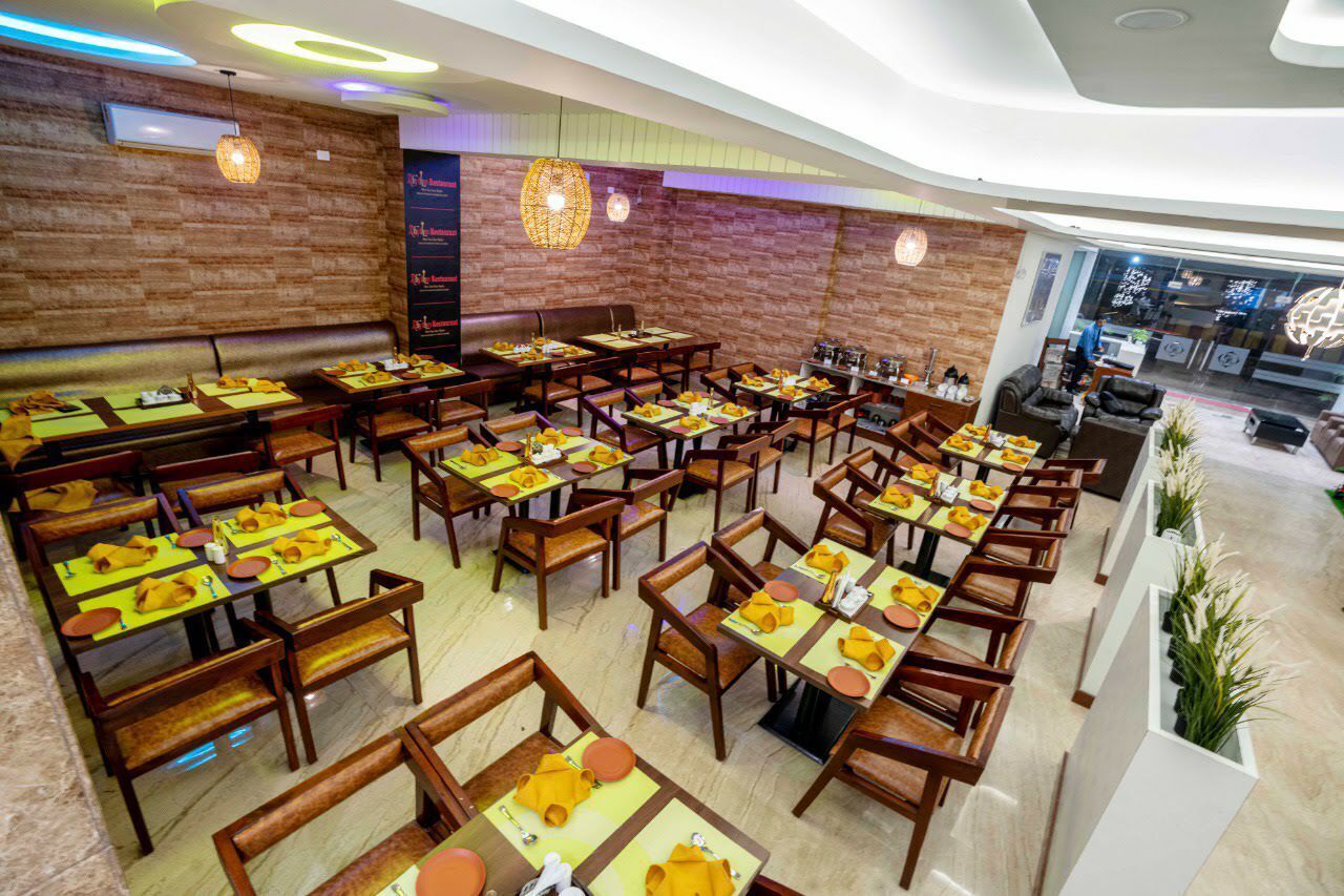 Un restaurant doté de nombreuses tables et de banquettes, de meubles en bois et d’un mur en briques.
