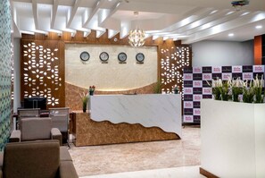 A reception area with a marble counter, four clocks, and a decorative wall panel. - Hotel ORIGIN Hyderabad Airport (Hyderabad)